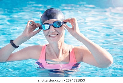 Active fitness, exercise senior  woman (over age of 50) in sport goggles, cap in the swimming pool before water sport, aerobics smiling in summer day. Healthy lifestyle. - Powered by Shutterstock