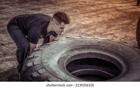 Active Fitness Man Lifts Heavy Wheels On An Outdoor Training Ground. Cross Training. Healthy Lifestyle