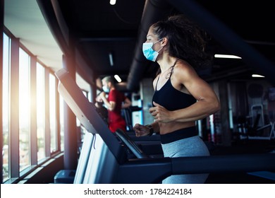 Aktive Fitness-Frau, die eine hygienische Schutzmaske trägt, während sie im Fitnessstudio trainiert, um sich und andere gegen Coronavirus oder Covid-19 zu schützen. Bleiben Sie sicher und gesund.