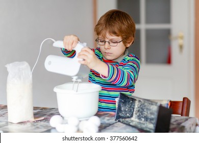 Active Funny Blond Little Kid Boy N Glasses Baking Apple Cake And Muffins In Domestic Kitchen. Happy Child Having Fun With Working With Mixer, Flour, Eggs And Fruits At Home.