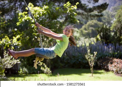 Active girl swinging on garden rope swing having fun at camera - Powered by Shutterstock