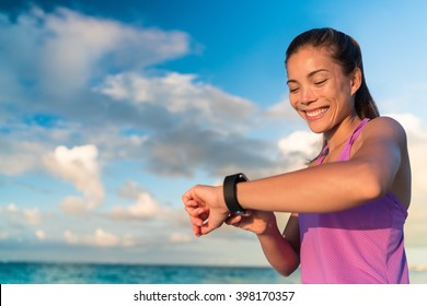 Active Girl Using Fitness Tracker Smart Watch Jogging On Summer Nature Outdoors Looking At Health Data During Sports Activity Touching The Screen Of Her Smartwatch.