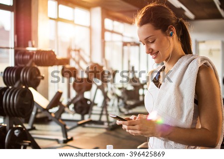 Active girl using smartphone in fitness gym.
