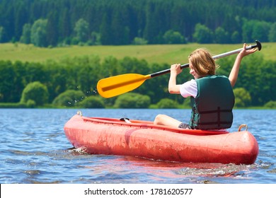 Active happy boy in summer holiday. Teenage school boy having fun enjoying adventurous experience kayaking on lake on a sunny day during summer vacation.
