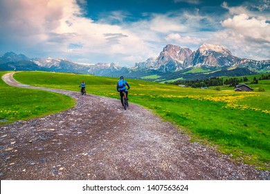 Active Happy Couple Cycling Outdoors. Healthy Lifestyle With Mountain Bike, Couple Cycling On The Mountain Road In The Alps, Dolomites, Italy, Europe