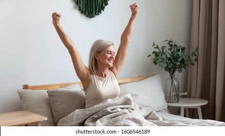 Active happy mature female wake up from good healthy sleep stretching sitting in bed at home, smiling positive senior woman awaken in comfortable bedroom feel optimistic welcome new day - Powered by Shutterstock
