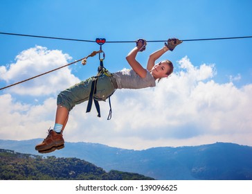 Active happy woman overhanging on tightrope in the mountains on blue sky background, climbing sport, mountaineering adventure, summer trekking concept - Powered by Shutterstock