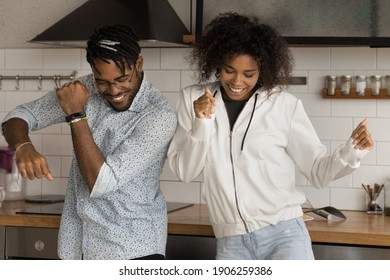 Active happy young black family couple enjoy modern dances at kitchen celebrate buying flat house of dream. Romantic millennial african lovers have fun dance disco together listen to energetic music - Powered by Shutterstock