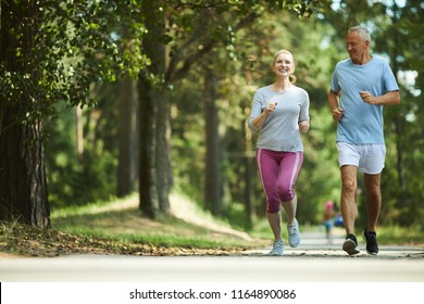 Active and healthy aged couple running in natural environment on summer morning - Shutterstock ID 1164890086
