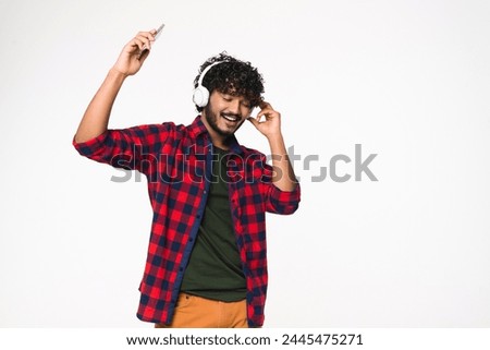 Active Hindi young man listening and dancing to the music in headphones isolated over white background. Indian fan enjoying playlist audio podcast radio