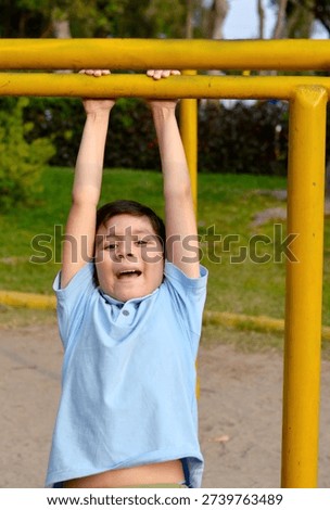 Active hispanic boy training on playground equipment.