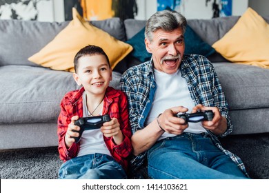 Active inspired man and his grandson enjoying new video game.. Sit on floor in living room. - Powered by Shutterstock