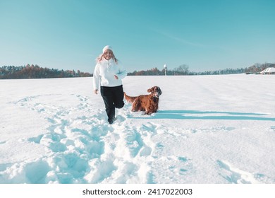 Active Irish Setter dog with woman running slow motion footage during the snowy walking, having fun in winter park during beautiful sunny winter day. High quality FullHD footage - Powered by Shutterstock