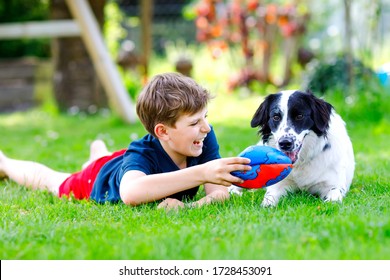 Active Kid Boy Playing With Family Dog In Garden. Laughing School Child Having Fun With Dog, With Running And Playing With Ball. Happy Family Outdoors. Friendship Between Animal And Kids