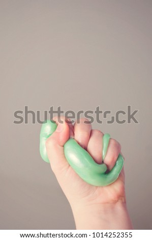 An active kid squeezing fluffy green slime: Slime is a funny toy to activate  playing kids.