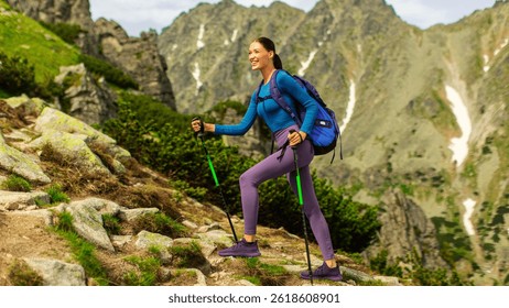 Active lady with backpack using trekking poles and hiking in mountains, enjoying beautiful views, full length shot, side view, free space