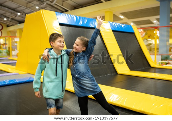 Active leisure. Children having fun on\
trampoline in entertainment center, childhood and sporty lifestyle.\
Boy and girl in leisure spotr center for kids. Brother and sister\
indulge on trampolines.