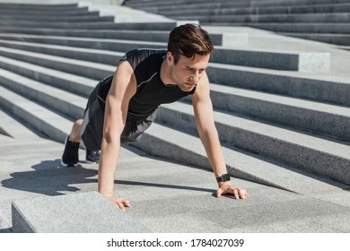 Active leisure and motivation. Millennial guy in sportswear with fitness tracker push up the city stairs at sunlight, free space