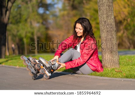 Active leisure. A sportive girl is rollerblading in an autumn park.