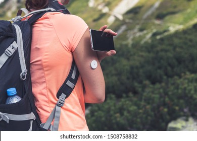 Active Life Of Diabetics, Woman Hiking And Checking Glucose Level With A Remote Sensor And Mobile Phone, New Technology Sensor Checkup Glucose Levels Without Blood. Diabetes Treatment.