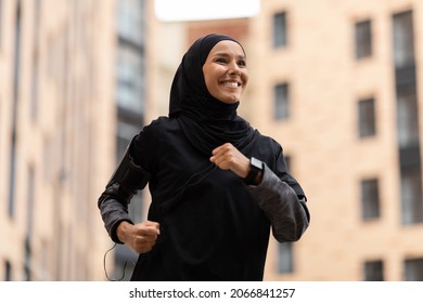 Active Lifestyle. Portrait Of Happy Young Muslim Woman In Modest Sportswear Jogging Outdoors, Athletic Islamic Lady In Hijab Running On Urban City Street, Enjoying Training Outside, Closeup - Powered by Shutterstock