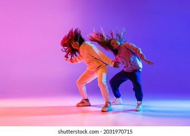 Active lifestyle  Two beautiful hip  hop dancers in motion gradient pink purple neon background  Sport achievement  expression  Concept dance  youth  hobby  dynamics  movement  action  ad