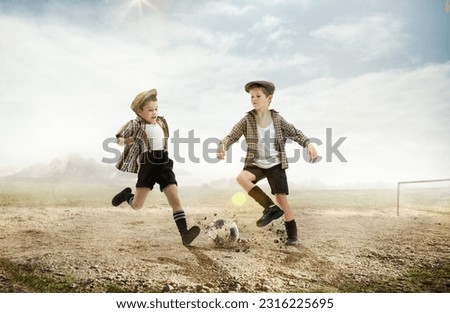 Active little boys, children in retro style clothes playing football outdoors on a daytime. warm sunny day on countryside. Concept of sport, childhood, retro style, active lifestyle, summer vacation