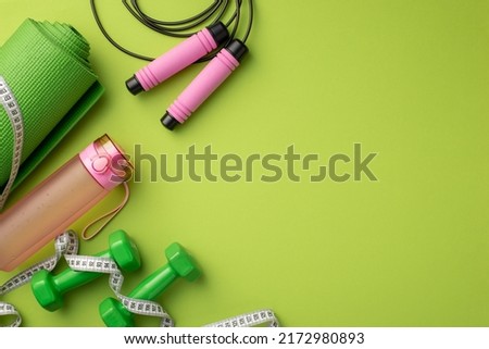 Active living concept. Top view photo of sports mat tape measure pink bottle of water skipping rope and dumbbells on isolated green background with empty space