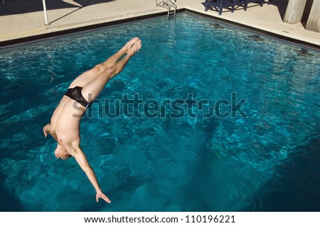 Active male diver diving into the pool