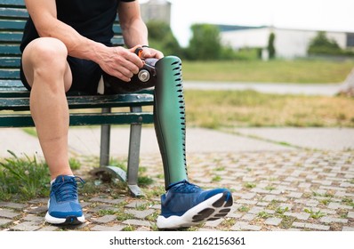 Active Man Adjusting His Prosthetic Leg Before Walking Outdoor In The Park