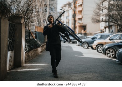 Active man in casual wear holding a mountain bike over his shoulder while walking on an urban sidewalk. - Powered by Shutterstock
