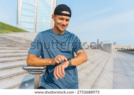 Active man checking his smart watch on modern concrete steps during a sunny outdoor training session