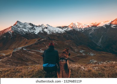 Active Man and Dog watching Sunrise in High Alps Mountains. Adventure Lifestyle and Friendship. - Powered by Shutterstock