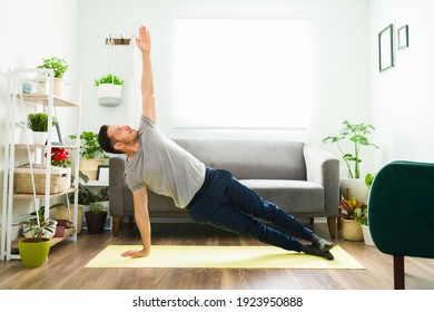 Active man doing a home workout. Fit man in his 30s in a side plank strengthening his body with a yoga routine