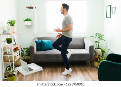 Active man with a healthy lifestyle running in place in the living room. Fit young man doing a high intensity interval training 