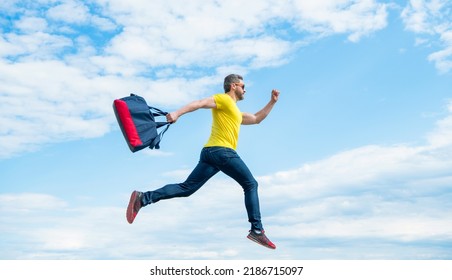 Active man running with sporty bag midair sky background, sport