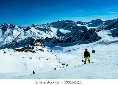 Active man snowboarder riding on slope. Snowboarding closeup. Winter panorama of mountains with ski slopes and skiing people, Austrian Tirol, Alps. - Shutterstock ID 1332361283