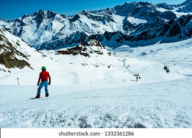 Active man snowboarder riding on slope. Snowboarding closeup. Winter panorama of mountains with ski slopes and skiing people, Austrian Tirol, Alps. - Shutterstock ID 1332361286