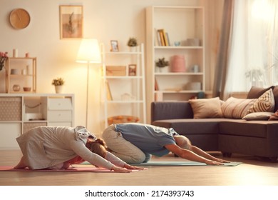 Active Mature Couple Resting In Childs Pose While Practicing Yoga Together At Home