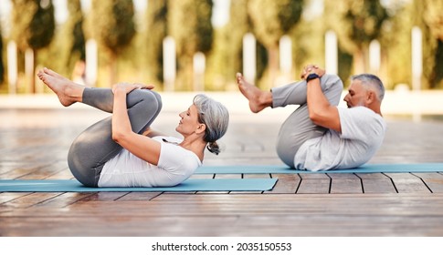 Active mature family man and woman doing yoga exercise  lying on mat hugging her knees to chest after yoga practice outdoor in park, healthy active senior couple doing stretching exercises   