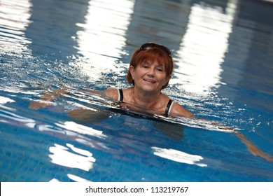 Active Mature Lady Swimming In Swimming Pool, Smiling.