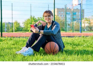 Active Mature Woman With Basketball Ball And Smartphone, Outdoor