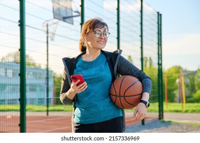 Active Mature Woman With Basketball Ball And Smartphone, Outdoor