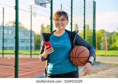 Active Mature Woman With Basketball Ball And Smartphone, Outdoor