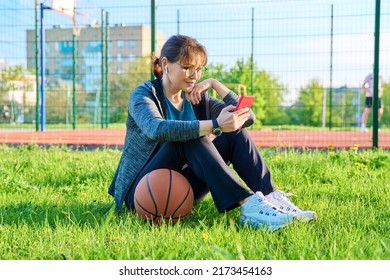 Active Mature Woman With Basketball Ball And Smartphone, Outdoor