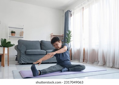 Active mature woman doing stretching exercise in living room at home. Fit lady stretching arms and back while sitting on yoga mat.  - Powered by Shutterstock