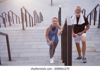 Active Middle Aged Couple, Man And Woman In Sportswear Looking At Camera, Walking Up The Stairs After Exercising Together Outdoors