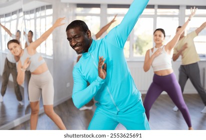 Active middle-aged African-American man practicing hip-hop dance in training hall during dancing classes - Powered by Shutterstock