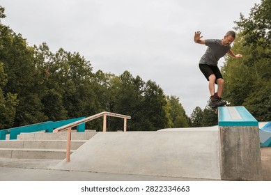 Active middle-aged man performing an aggressive inline skate grind trick on a ledge at a concrete park