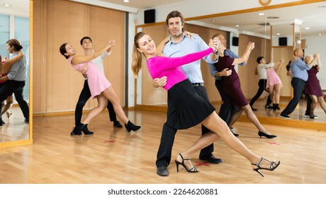Active middle-aged pair practicing ballroom dance in training hall during dancing-classes. Pairs training ballroom dance